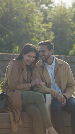 Video-Vertical-De-Una-Pareja-Musulmana-En-Una-Cita-Hablando-Sentados-Juntos-En-El-Parque-De-La-Ciudad